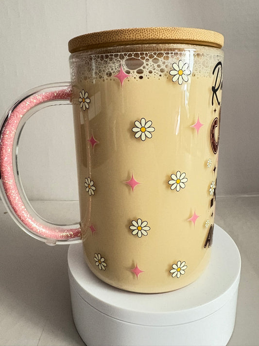 Beige mug with floral designs, a pink handle, and wooden lid on a white surface.